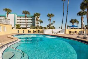 a swimming pool at a resort with palm trees at Days Inn by Wyndham Cocoa Beach Port Canaveral in Cocoa Beach
