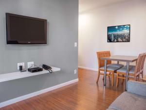 a dining room with a table and a television on a wall at Mercure Sao Paulo Berrini in São Paulo