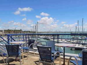un groupe de chaises et de tables sur un quai avec des bateaux dans l'établissement ibis Granville Port De Plaisance, à Granville