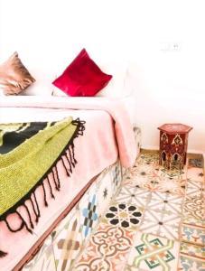 um quarto com uma cama com almofadas vermelhas e uma mesa em Dar merouan em Essaouira