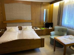 a bedroom with a bed and a desk and a chair at Hotel Waldlust in Baiersbronn