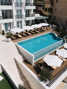 an outdoor swimming pool with lounge chairs and umbrellas at Villa Garden in Sveti Stefan