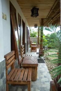 a porch with two wooden benches on a house at Tastura Homestay in Praya