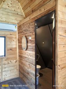 La salle de bains est pourvue de toilettes et d'un mur en bois. dans l'établissement Lord Sunrise- Shanker Farm Villa, à Kīhīm