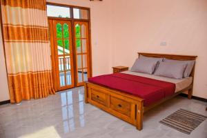 a bedroom with a wooden bed with a red blanket at Saayoo Resort in Negombo