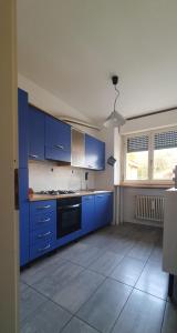 een grote keuken met blauwe kasten en een raam bij Appartamento Matilde. Spazio, comodità e relax! in Gavirate