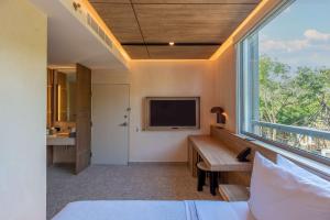 a bedroom with a large window and a tv at Motto By Hilton Tulum in Tulum