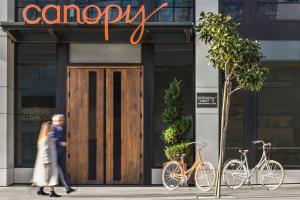 Eine Frau, die vor einer Tür eines Ladens läuft. in der Unterkunft Canopy by Hilton San Francisco SoMa in San Francisco