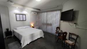 una camera con letto bianco e TV a schermo piatto di Recanto do Sossego- Espaço Jean a Santa Cruz do Sul