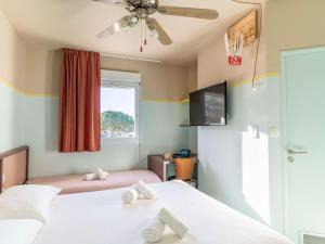 1 Schlafzimmer mit 2 Betten, einem TV und einem Fenster in der Unterkunft greet hôtel Pont du Gard - Route d'Avignon in Estézargues