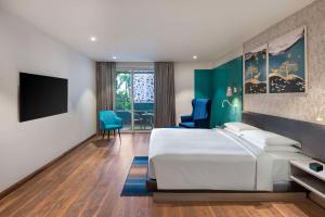 Hyatt Place Goa Candolim في كاندوليم: غرفة فندقية بسرير وتلفزيون بشاشة مسطحة