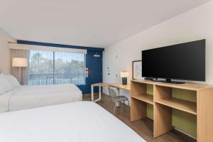 a hotel room with a bed and a flat screen tv at Spark by Hilton Hilton Head Island in Hilton Head Island