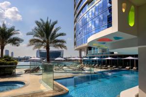 ein Hotelpool mit Stühlen und Sonnenschirmen in der Unterkunft Hilton Dubai Creek Hotel & Residences in Dubai