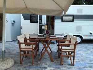 a wooden table and chairs with an umbrella and a van at Delightful RV Camper In a Peaceful Area near Sea. in Skala Fourkas