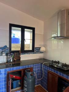 a kitchen with blue tiles on the counter and windows at พนาสนธิ์แหลมหินรีสอร์ท in Ban Laem Hin