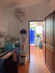 una cocina con fregadero y una puerta a una habitación en พนาสนธิ์แหลมหินรีสอร์ท en Ban Laem Hin