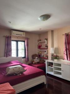 1 dormitorio con cama rosa y ventana en พนาสนธิ์แหลมหินรีสอร์ท en Ban Laem Hin