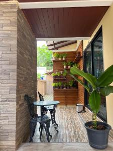 a patio with a table and chairs and a potted plant at พนาสนธิ์แหลมหินรีสอร์ท in Ban Laem Hin