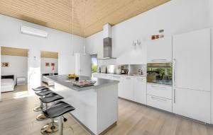 a kitchen with white cabinets and a island with bar stools at Gorgeous Home In Tarm With Sauna in Tarm