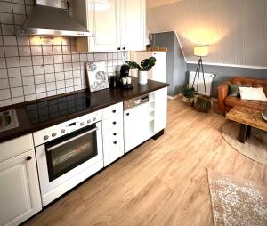 a kitchen with white cabinets and a wooden floor at Ferienwohnung Auszeit Norddeich Hannes I 5 Minuten zu Fuß zum Meer in Norddeich