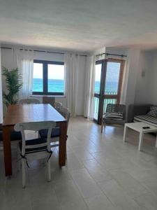 un salon avec une table et des chaises et l'océan dans l'établissement Apartamento Alborada Villas2meet Mallorca, à Can Picafort