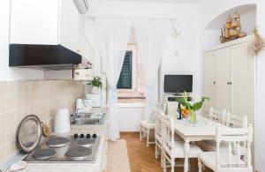 a white kitchen with a sink and a table at Apartments Adriana Flora in Dubrovnik
