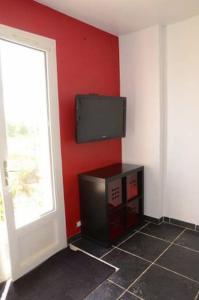 Habitación con TV de pantalla plana en una pared roja. en Maison dans son écrin de verdure, en Plouvien