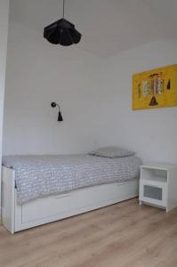 1 dormitorio con 1 cama blanca y mesita de noche en Maison dans son écrin de verdure, en Plouvien