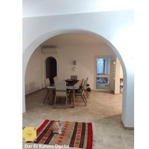 a dining room with a table and chairs and a cat at Dar El Kahina Djerba in Mezraya