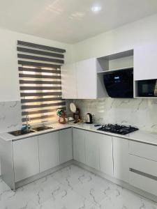 a white kitchen with white cabinets and a stove at 1 Bedroom Flat Sangotedo Ajah in Sangotedo