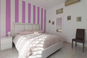 1 dormitorio con 1 cama con rayas rosas y blancas en Maison Lillina, en Sorrento
