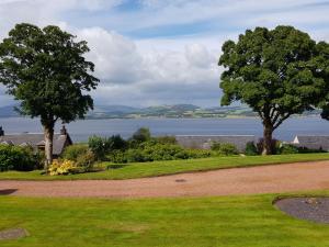 a park with two trees and a body of water at Glen Self-catering Apartment in Port Glasgow