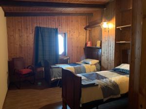 a bedroom with two beds and a window and a chair at Bielmonte Appartamenti in Bielmonte