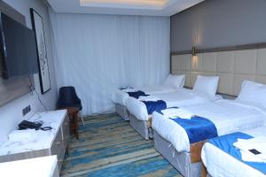 a hotel room with three beds and a flat screen tv at فندق بوابة منى in Al ‘Azīzīyah