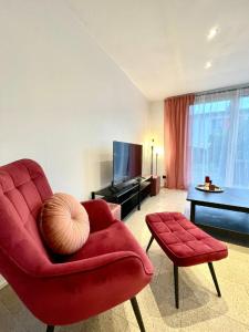 un salon avec une chaise rouge et une télévision dans l'établissement Geräumiges Ferienhaus in Koblenz, à Coblence