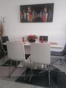 a dining room table with white chairs and a painting at Andros Residence in Limassol