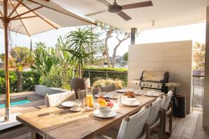 an outdoor dining table with chairs and an umbrella at Villa Lujo Castelldefels Barcelona in Castelldefels