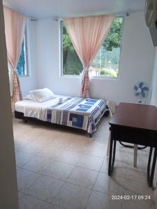um quarto com uma cama, uma secretária e uma janela em Servituristicos La Esmeralda em Santa María