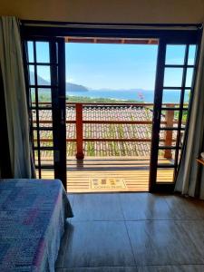 a bedroom with a view of the ocean from a balcony at Burung Flats Itamambuca - Hospedagem com vista para o mar in Ubatuba