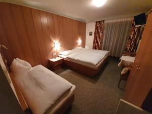 ein Hotelzimmer mit 2 Betten und einem Stuhl in der Unterkunft Haus Monika und Haus Claudia in Mayrhofen