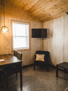 a room with a table and a chair and a television at Chalet - Abenaki Aventure in Pierreville