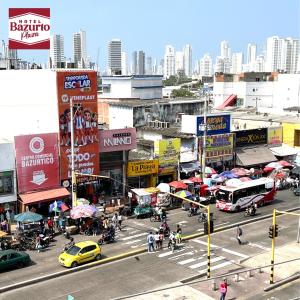 eine belebte Stadtstraße mit Autos, Menschen und Gebäuden in der Unterkunft Hotel bazurto plaza in Cartagena de Indias