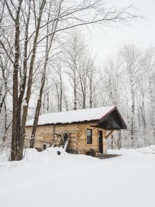 uma pequena cabana de madeira com neve no telhado em Chalet - Abenaki Aventure em Pierreville