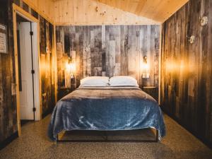 a bedroom with a bed and a wooden wall at Camping Abenaki Aventure - Les Chalets in Pierreville