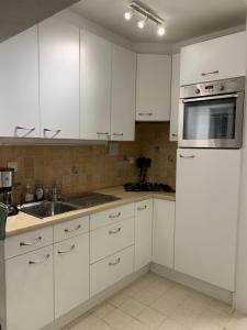 a white kitchen with white cabinets and a sink at Monte-Carlo in Koksijde