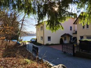 a house with a driveway next to a body of water at Ferienwohnung Prälank direkt am See in Neustrelitz