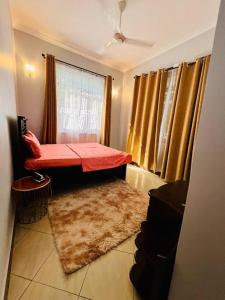 Pokój z czerwonym łóżkiem i oknem w obiekcie 1 Bedroom Apt - The Abode Mori w mieście Dar es Salaam