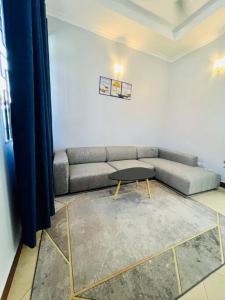 salon z kanapą i stołem w obiekcie 1 Bedroom Apt - The Abode Mori w mieście Dar es Salaam