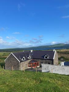 una casa in pietra su una collina in un campo di Valentia View a Portmagee