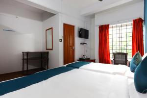 a bedroom with a large white bed and red curtains at HOTEL MUNNAR CENTRAL in Munnar